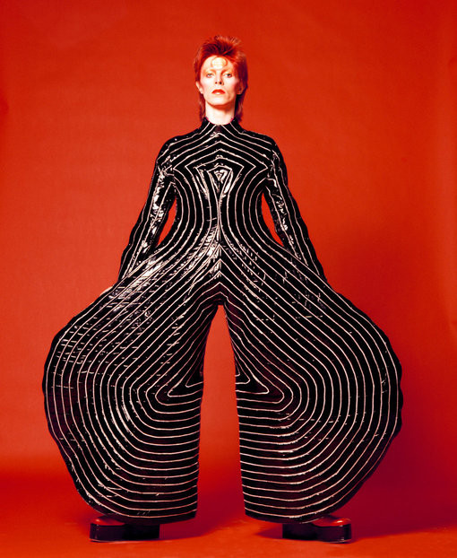 A black and white photo of David Bowie in a stripped bodysuit, showcasing an early example of anti-fashion pushing gender boundaries