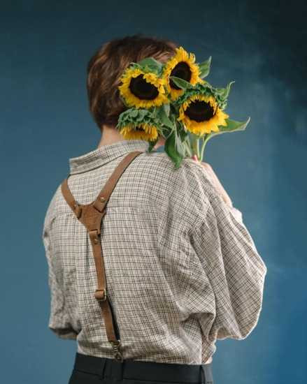 Boy holding sunflowers while wearing suspenders