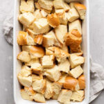 Cubed challah bread evenly spread in a white baking dish.