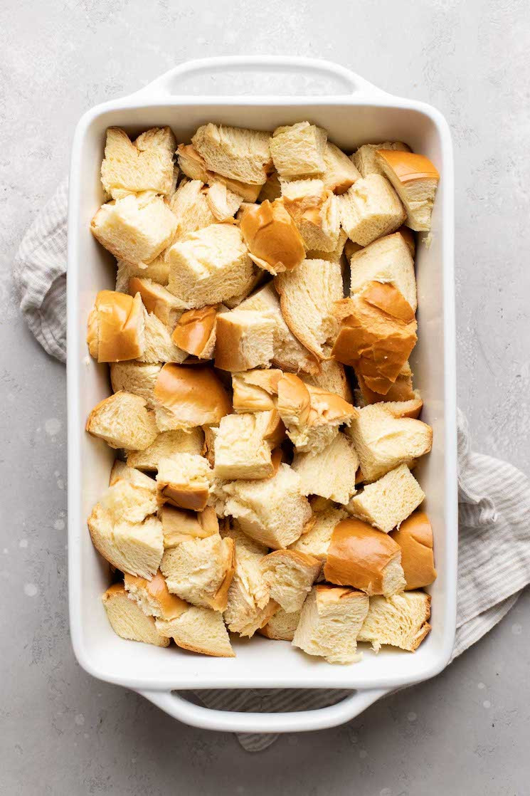 Cubed challah bread evenly spread in a white baking dish.