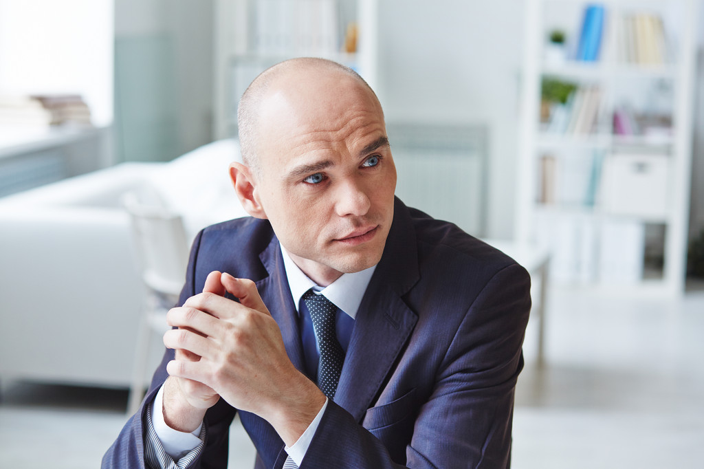 Bald man in a stylish navy suit standing confidently