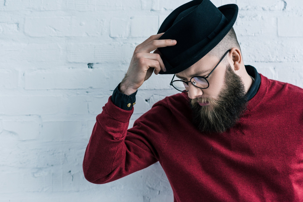 Bearded man in a red sweater wearing a stylish grey hat