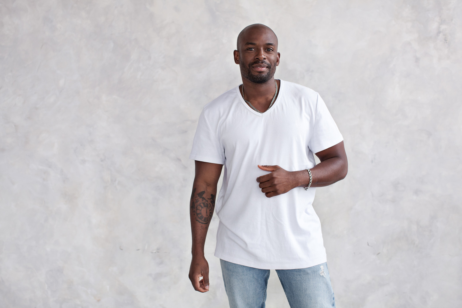 Man in a well-fitted V-neck white t-shirt and dark wash jeans