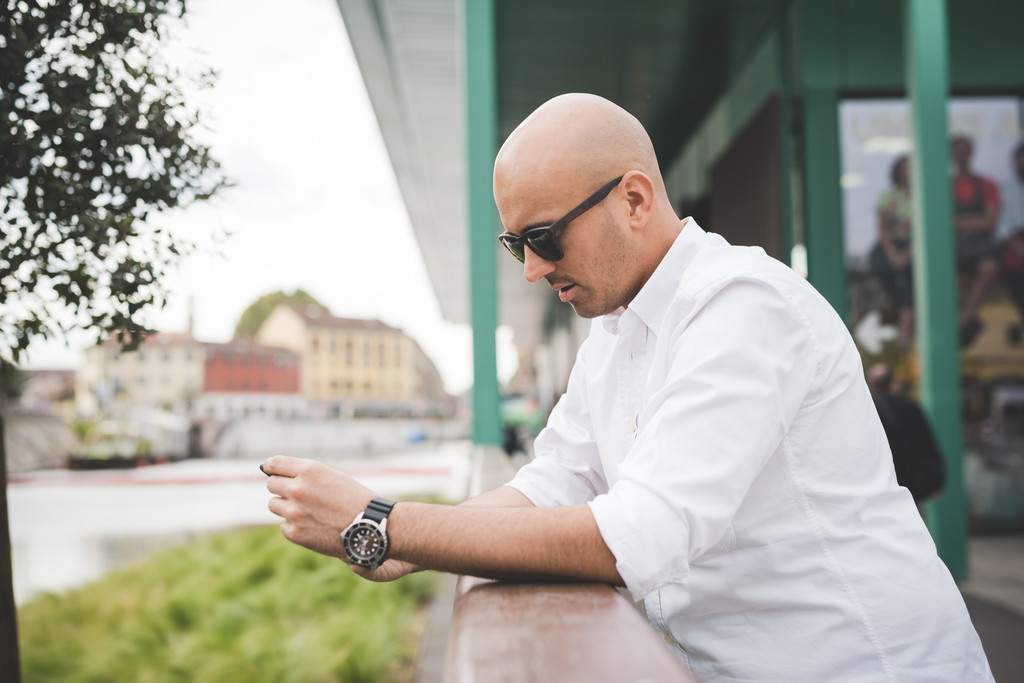 Bald man in a white shirt wearing sunglasses and a stylish watch
