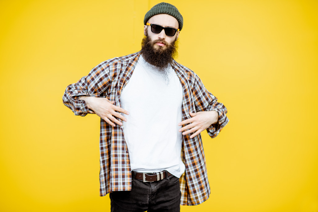 Bearded man wearing sunglasses and a plaid shirt in a hipster style
