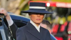 Melania Trump wearing a hat on Inauguration Day, showcasing her signature style with a striking navy hat and cream ribbon, blending tradition with a modern twist.