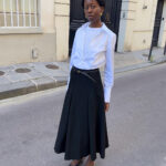 Man in gray pleated skirt and black top