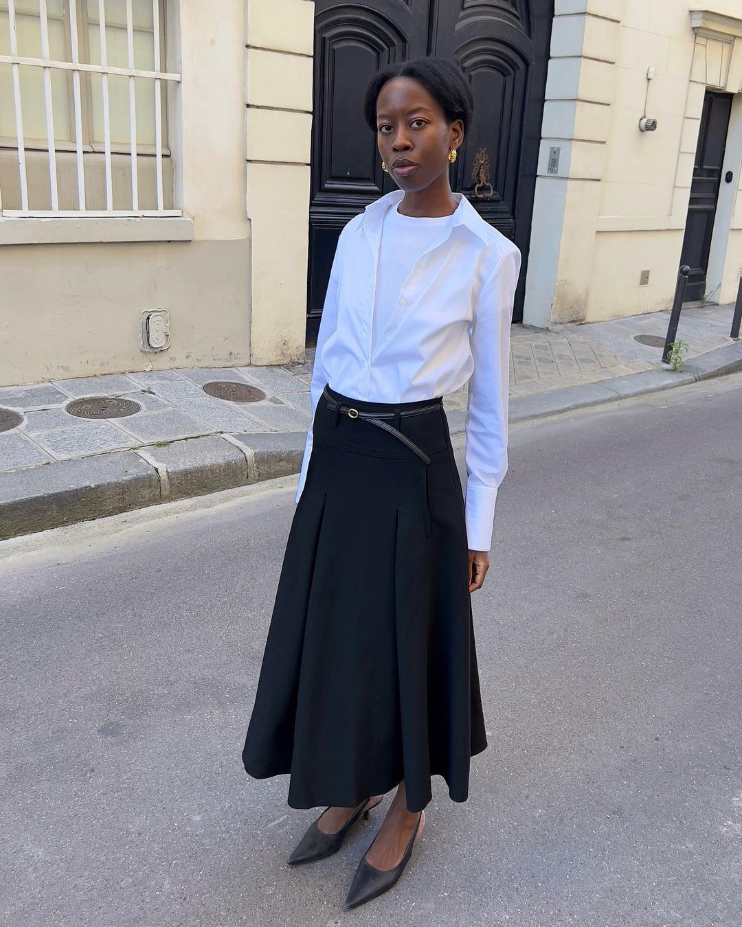 Man in gray pleated skirt and black top