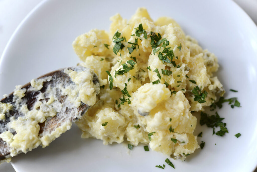 Old fashioned German potato salad with mayonnaise in a glass bowl