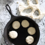 Homemade biscuits cut out and placed in cast iron skillet to be baked.
