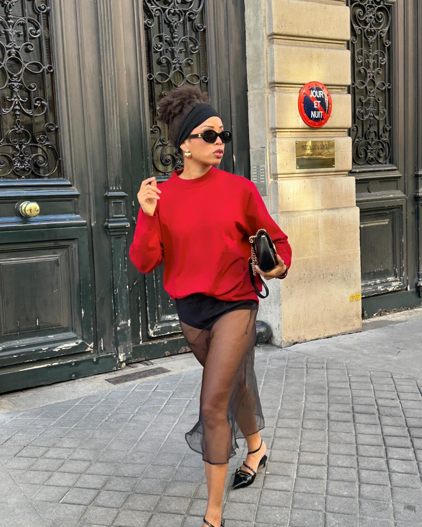 Man wearing a black sheer maxi skirt and red sweater, exuding bold winter style.