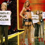 PETA protesters rush the stage as Gisele Bundchen poses during the Victoria’s Secret fashion show in 2002, showcasing ethical concerns about fur in fashion.