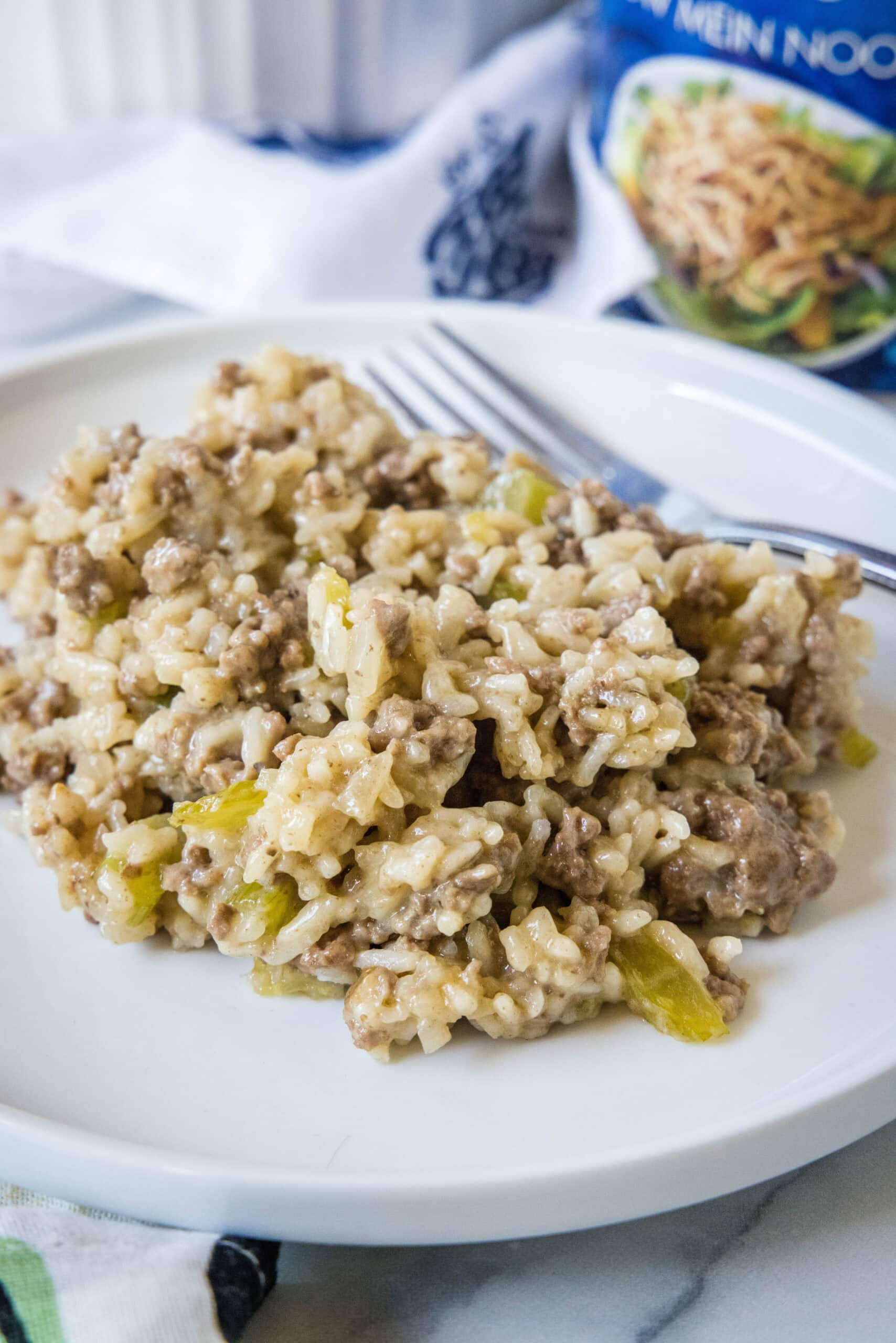 A serving of hamburger rice casserole next to a fork on a white plate.