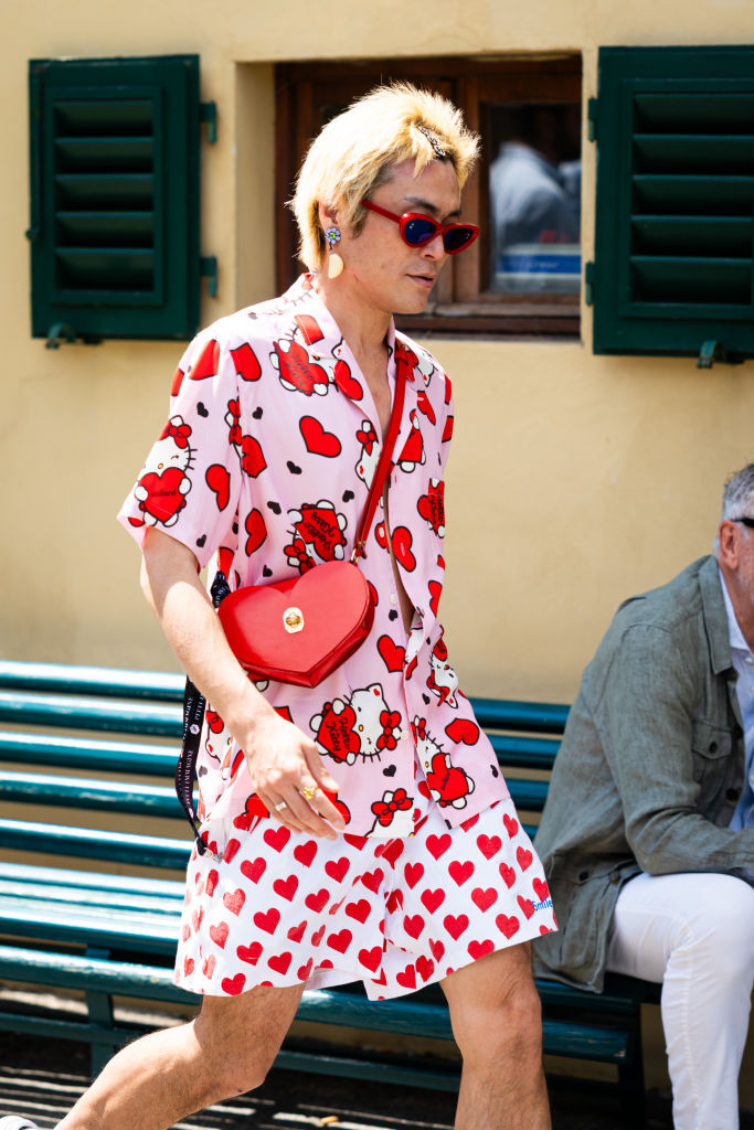A man wearing a stylish watch with a subtle Hello Kitty design, paired with a modern outfit.