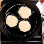 Close-up of golden brown hoe cakes cooking in a cast iron skillet