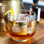 Close-up of a Honey Old Fashioned with a lemon twist, showcasing its rich color and texture