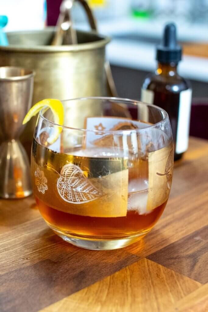 Close-up of a Honey Old Fashioned with a lemon twist, showcasing its rich color and texture