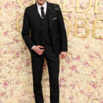 Adrien Brody at the 2025 Golden Globes in Thom Browne, a tailored black suit with a lapel broach.