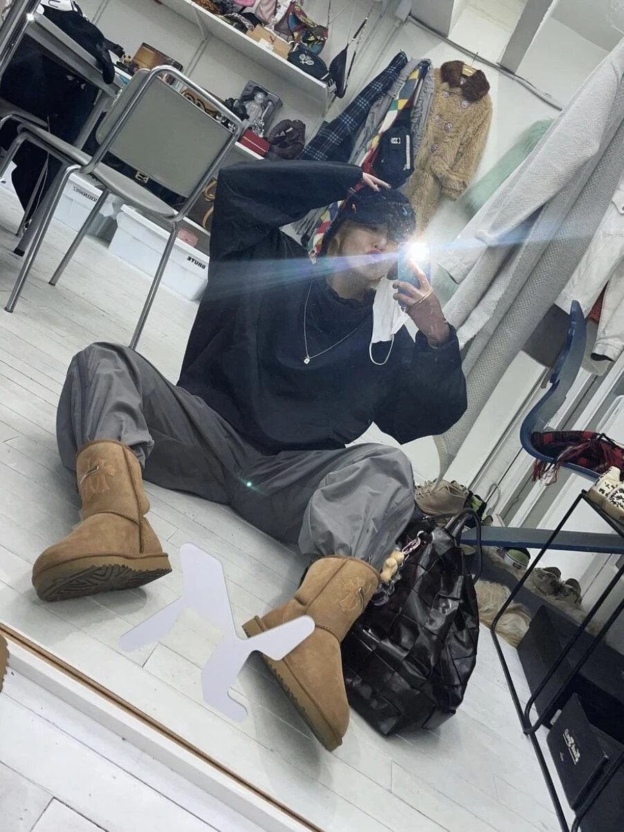 Korean icon wearing faux sheepskin boots matched with a black cap, pullover and baggy sweatpants for casual dark OOTD.