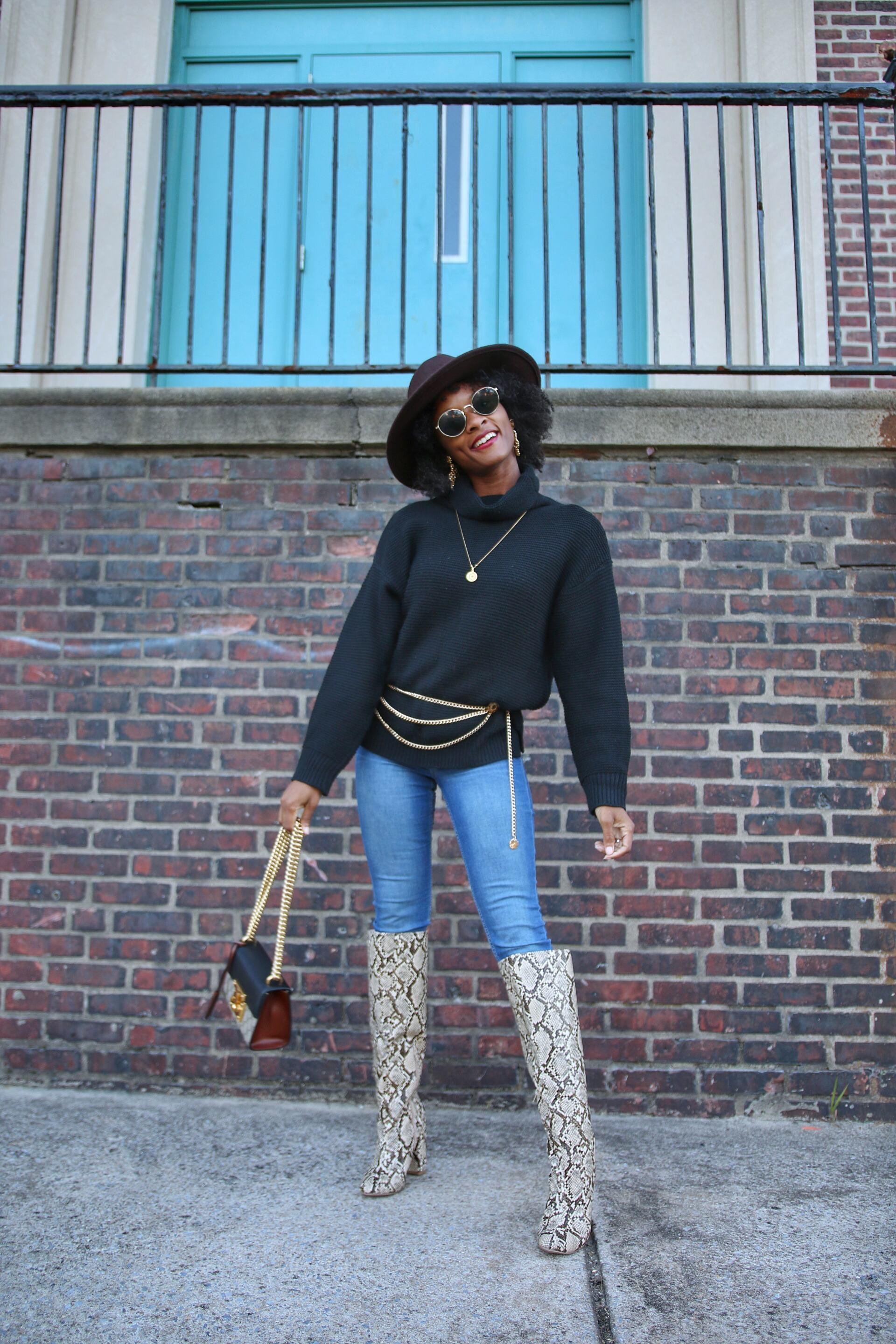 man wearing stylish black leather fashionista boots with silver buckles and studs, standing confidently in an urban setting