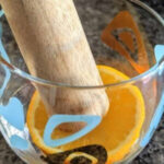 Muddling sugar, bitters, and cherry in an old fashioned glass