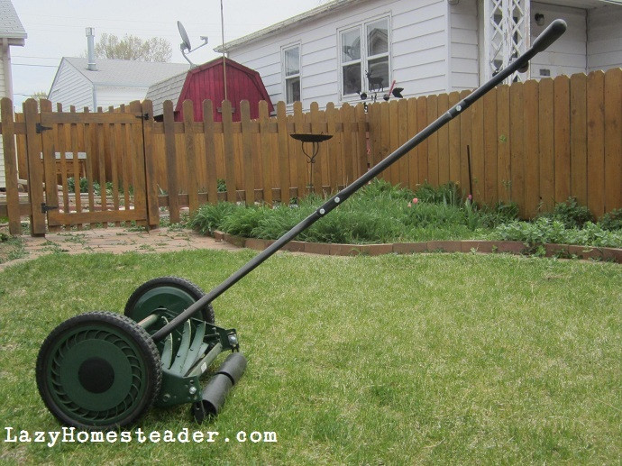 Man using an old fashion lawn mower in a backyard, cutting the grass neatly.