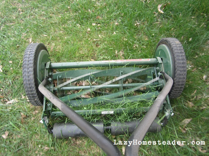Old fashion lawn mower parked in a garage, highlighting its compact size and ease of storage.