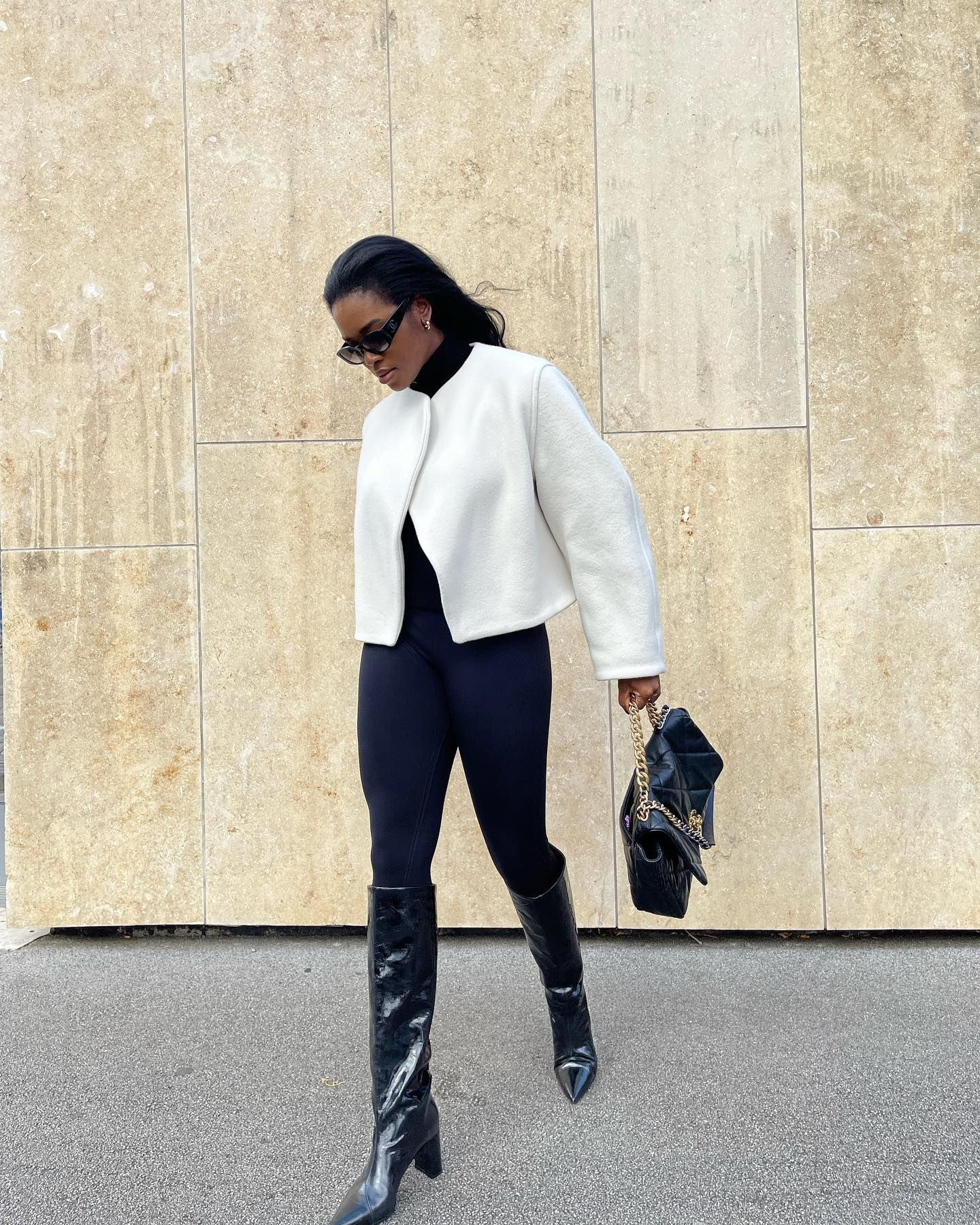 Man wearing black leather knee-high boots paired with dark jeans and a black leather jacket, showcasing a modern and edgy style.