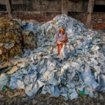 Man overlooking clothes piled high in a landfill, fashion waste statistics.
