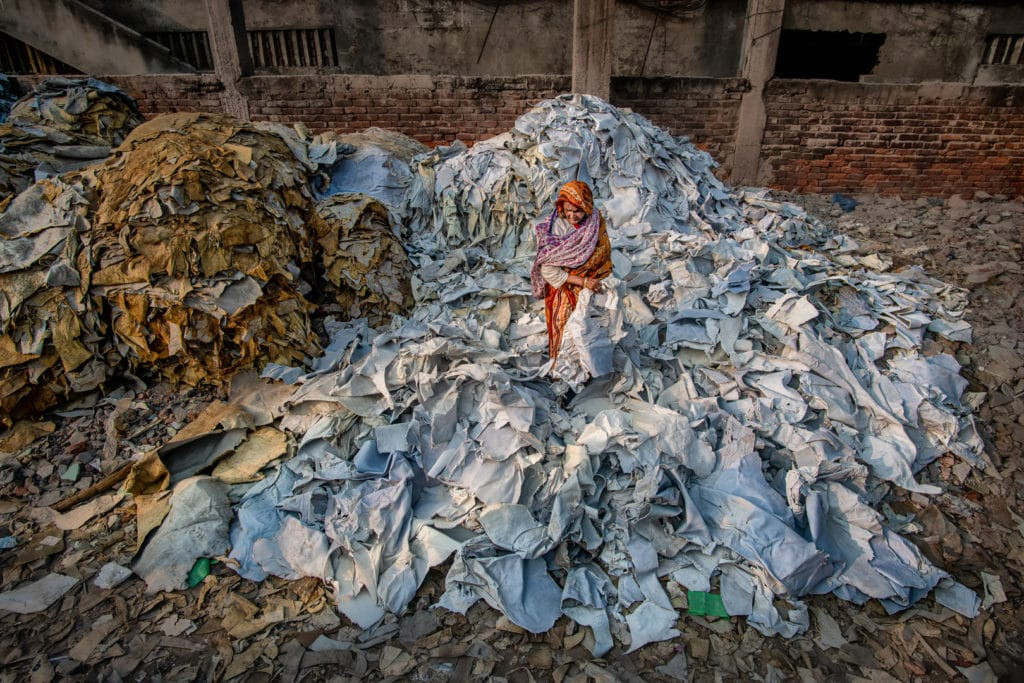 Man overlooking clothes piled high in a landfill, fashion waste statistics.