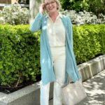 Woman wearing an organic linen cardigan, washable ivory silk blouse, and tile white jeans.