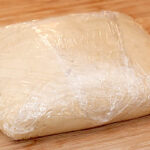 Finished dough shaped into a rectangle and wrapped in plastic wrap.