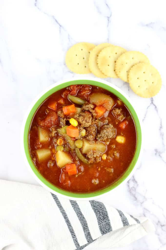 overhead photo of bowl full of homemade vegetable soup with round crackers nearby