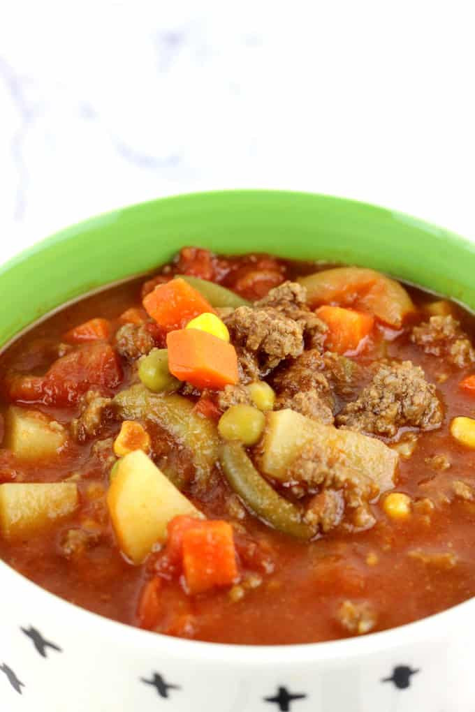 bowl filled with vegetable soup -chunks of potato, carrots, ground beef, green beans and corn with a tomato based broth.