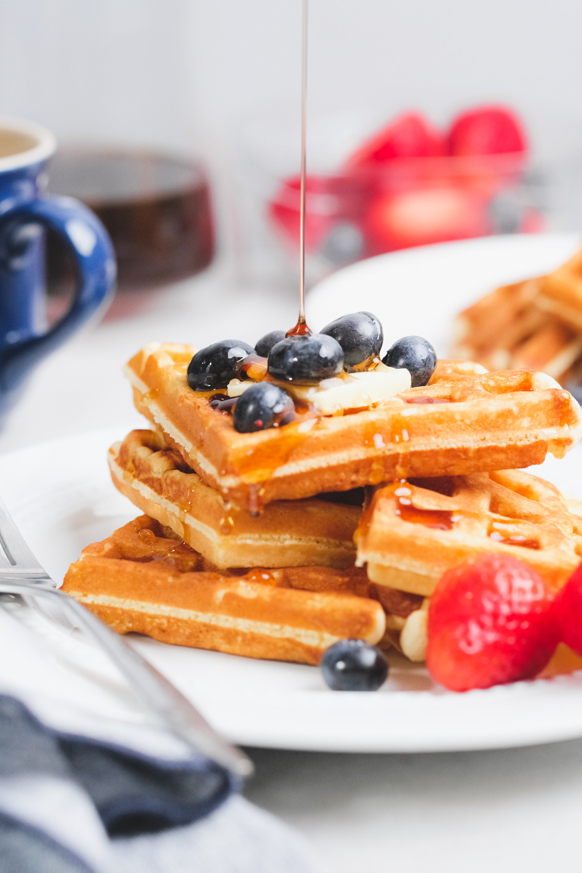 An old fashioned waffle iron on a kitchen counter with a metal latch to secure the waffle while cooking