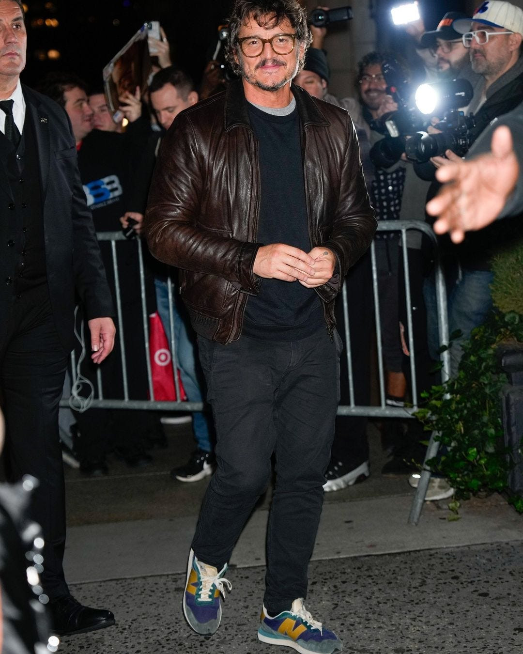 Pedro Pascal in leather jacket and sneakers giving strong 90s dad vibes, pairing a beat-up leather jacket with well-loved New Balance sneakers for a cool and effortless look.