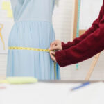 Close up of a seamstress measuring fabric with a tape measure