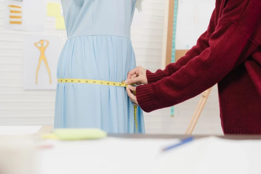 Close up of a seamstress measuring fabric with a tape measure