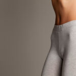 Close-up of a slim female abdomen on a white background showcasing fashion concerns