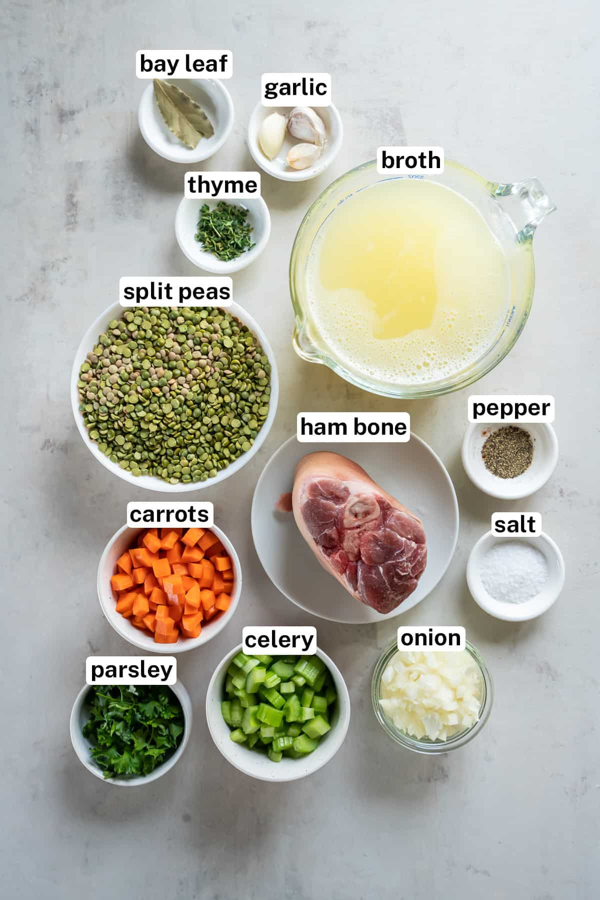 Ingredients for split pea soup including split peas, carrots, celery, onion, garlic, parsley, thyme, bay leaf, salt, pepper, ham bone, and chicken broth.