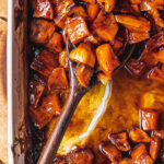 Overhead view of tender candied sweet potatoes baked in a casserole dish, featuring a rich, caramelized glaze