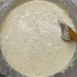Cornbread batter in a clear class bowl.