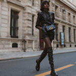 Thigh-high boots outfit shown on a woman wearing a black leather top with matching leather shorts and black flat tall boots for inspiration