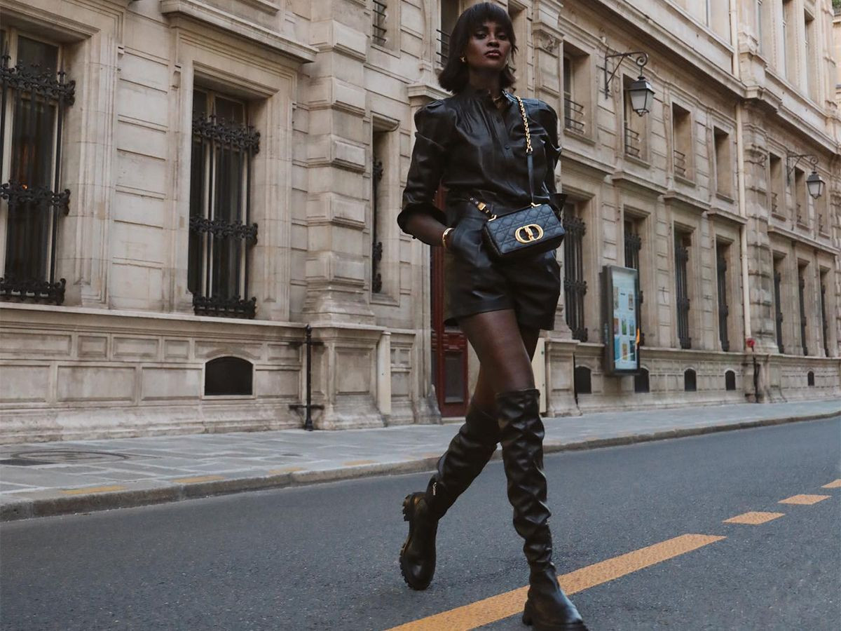 Thigh-high boots outfit shown on a woman wearing a black leather top with matching leather shorts and black flat tall boots for inspiration