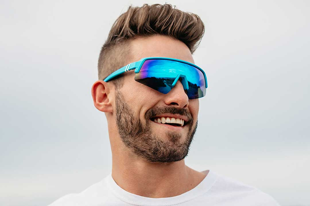 Three quarter view of young man wearing blue mono-lens sunglasses frame with blue tinted lenses