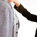 Woman getting her dress fitted in a tailor shop, emphasizing the importance of prioritizing fit for a flattering look.