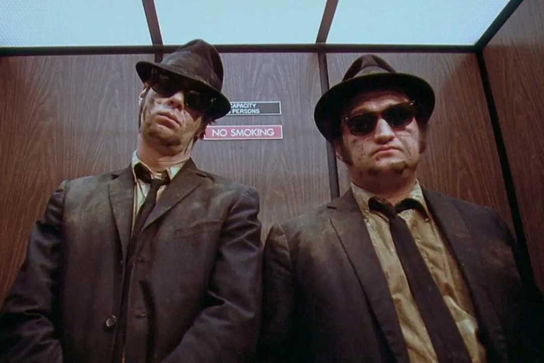 Two men in suits and dark sunglasses inside elevator from the 1980 film The Blues Brothers