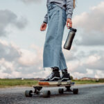 Skateboarder with checkerboard vans, baggy jeans, graphic tee, and baseball cap embodies skate fashion