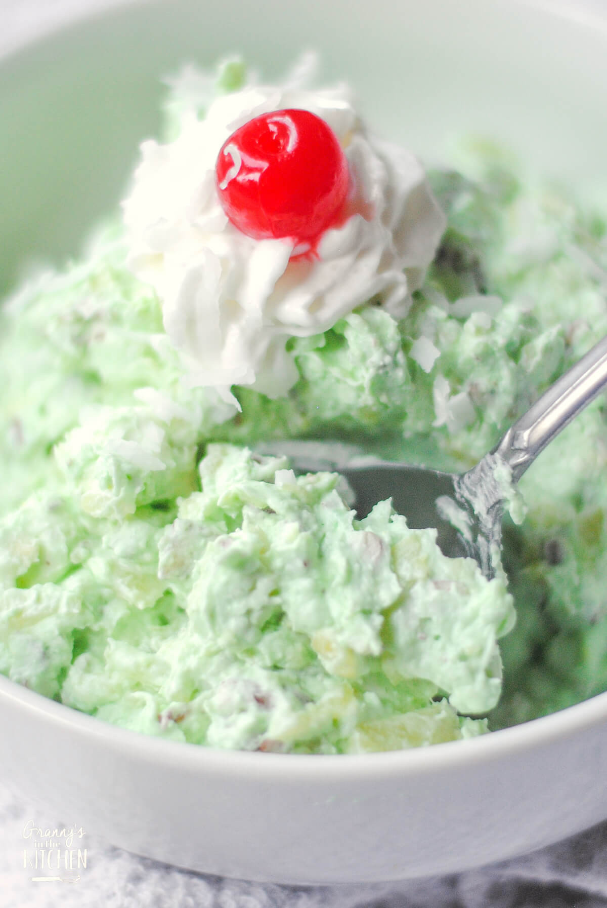 Bowl of green pistachio fluff salad with a spoon