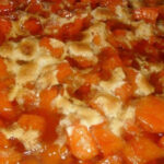 Close-up of candied yams with marshmallows, highlighting the sweet potatoes baked in a brown sugar syrup until tender and topped with mini marshmallows, showcasing the dish's texture and inviting appeal.